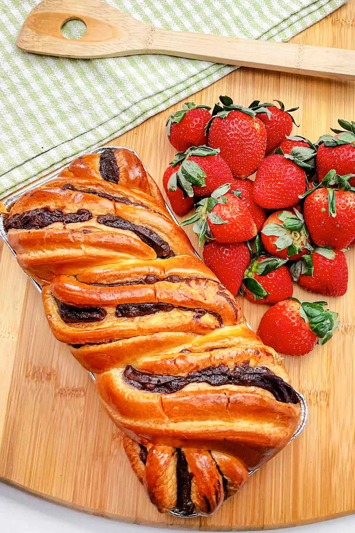 Loaf of Chocolate Brioche Bread and fresh strawberries sitting on a cutting board.