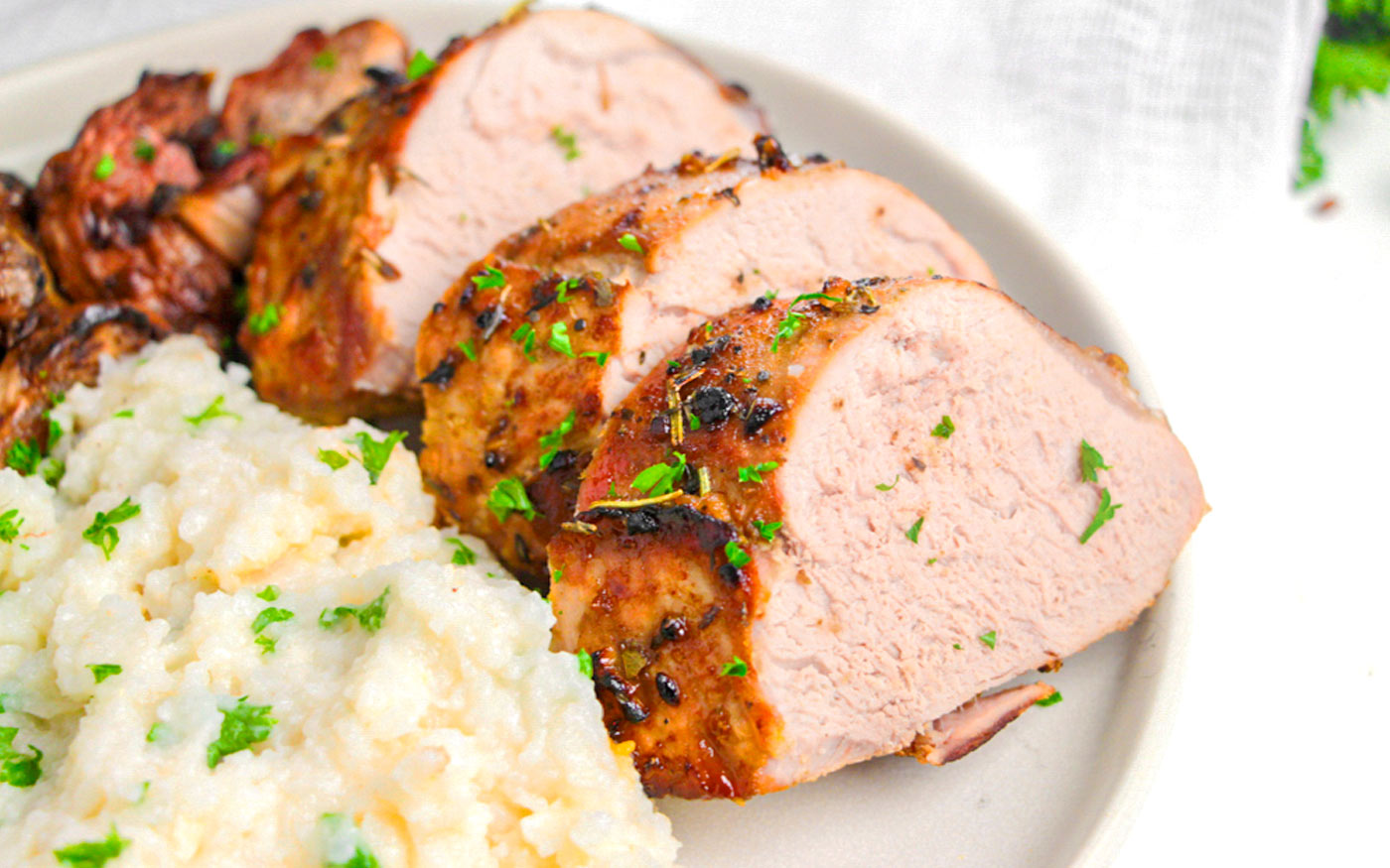 Air fryer pork tenderloin sliced and displayed on plate with mashed potatoes.