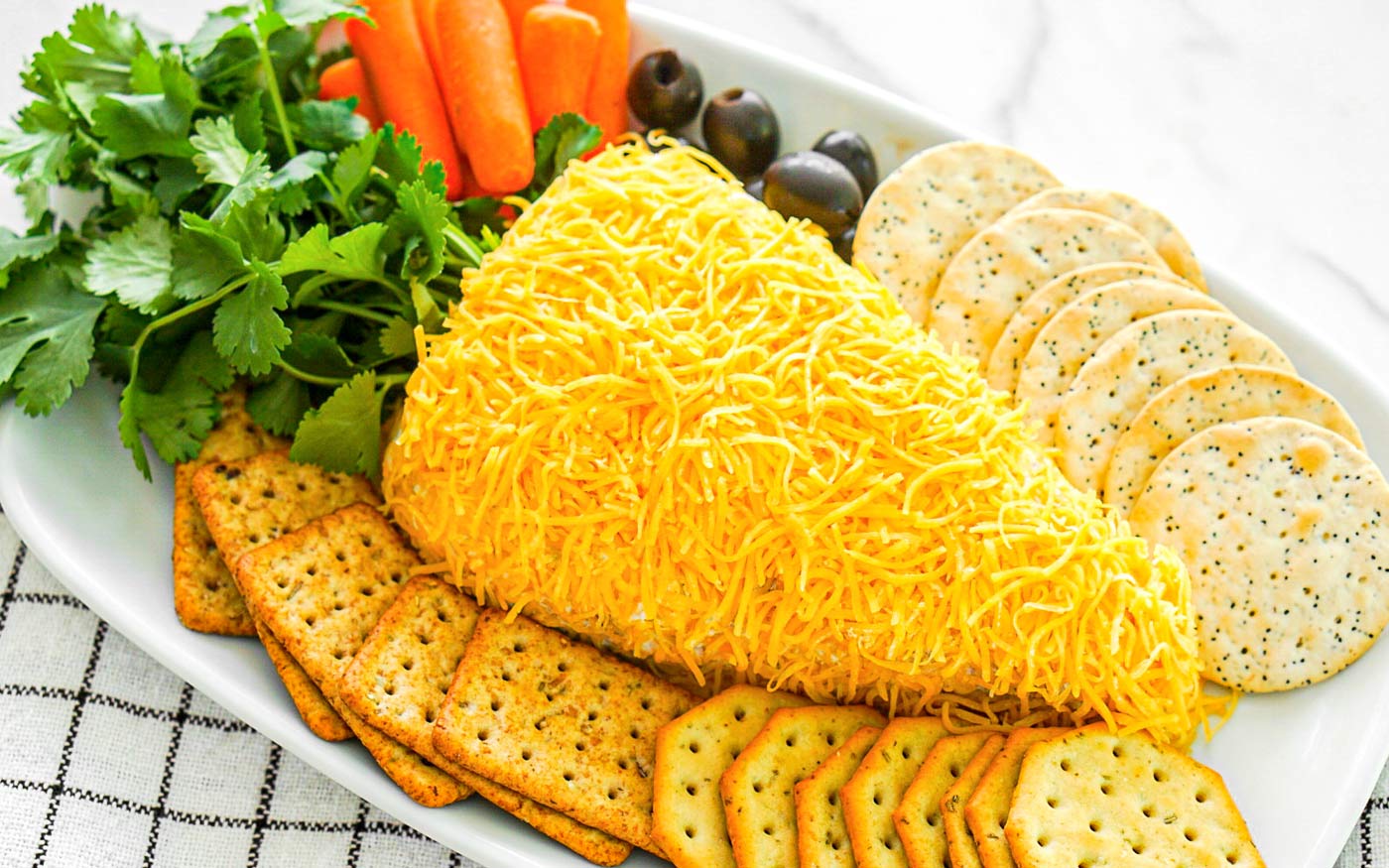 Easter cheese ball shaped like a carrot on a platter with crackers.